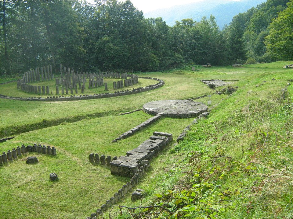 Suprafața Sarmizegetusei este o iluzie; practic, artefactele și monumentele sale sunt ca piese de șah care au fost mutate pe o tablă în carouri. Oricum, originile și adevărata sa semnificație sunt ascunse adânc sub pământ. În plus, fiecare civilizație este stratificată peste predecesorii săi; cu cât săpăm mai adânc, cu atât originile noastre sunt mai antice. Deci, trebuie să ne întrebăm cine a existat acolo înaintea traco-geto-dacilor și cine erau zeii lor? ce s-a descoperit în timpul săpăturilor arheologie? De exemplu, în anul 2000, a fost găsită una dintre cele mai decisive descoperiri din istoria dacilor geți: 15 brățări de aur la Sarmizegetusa care au zguduit temelia istoriei României. Aceste brățări erau minereu de aur extras din munții Carpați, Roșia Montană și regiunea Sarmizegetusa. În plus, am menționat de mai multe ori că Sarmizegetusa era o operațiune minieră și un observator astronomic. În concluzie, dacii au asamblat o armată puternică, construind fortificații în toată regiunea pentru a proteja comoara depozitată la Sarmizegetusa, și practicile lor religioase.Mai mult, geto-dacii au creat un sistem foarte avansat de extragere a minereului de aur pe care nu îl putem replica astăzi din punct de vedere tehnic sau alchimic. În cele din urmă, aurul a fost amestecat cu o cantitate mică de argint pentru a spori culoarea și rezistența brățărilor; geto-dacii erau maeștri ai alchimiei, un dar primit de la zei.Putem vedea acest concept de arhitectură ezoterică în construcția orașului geto-dac, pe care acum îl numim cele 9 sanctuare și cetăți dacice supraviețuitoare: Apulon, Sarmisegetuza Regia, Costești, Blidaru, Fetele Albe, Piatra Roșie, Bănița, și Căpâlna; toate așezate într-o aliniere cu muntele lor sacru, Godeanu (Godeanu reprezintă locația a ceea ce mulți cercetători consideră că este misteriosul „Kogaion”). Fiecare dintre aceste locații corespundea unui nivel de inițiere în care fiecare elev experimenta cunoașterea vechilor arieni și a lui Zamolxis. La absolvire, adepților li s-ar fi acordat o brățară în formă de dragon. Aceste brățări erau diplome; fiecare model includea inscripția unui scut și o creastă care ar simboliza o stemă. Numărul de creste și lungimea spiralelor de pe brățară ar identifica gradul de cunoaștere al individului, obținut de la ordinul dragonului și școala misterului Zamolxian. Regele Burebista, care a fondat acest sistem în munții Orăștiei, a făcut acest lucru pentru o eficacitate optimă; a vrut să păstreze totul localizat și cuprins cu orașul Dacia. Prin urmare, Munții Orăștiei și văile lor au fost cea mai abundentă si satisfăcătoare locație astronomică pentru construirea rețelelor și sistemelor de temple și fortărețe.Zamolxis este punctul intermediar sau Stația de Transfer pentru toate energiile universale, „Controlul Volumului” .Acest sistem este pus în aplicare pentru alinarea conștiinței în organismul nostru. Astfel, Zamolxis a fost versiunea a ceea ce acum numim rai. Anticii își investeau timpul pe pământ aducând-ul jos pe Zamolxis; priveau cerul nopții și construiau constelații în arhitectura lor pentru a-i atrage sau a pentru a fi aproape de zei.